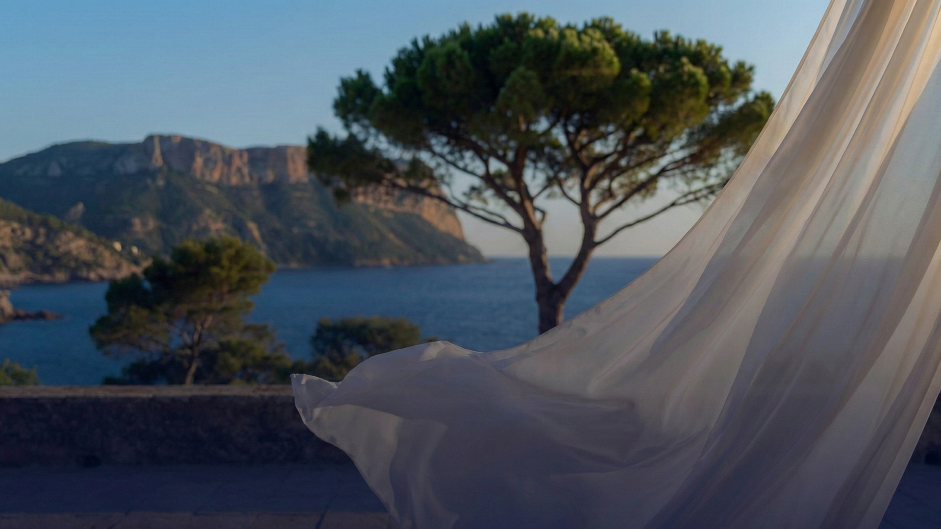 Voile de soie blanc flottant face à la mer sur la Riviera méditerranéenne au coucher du soleil – univers Crystaal
